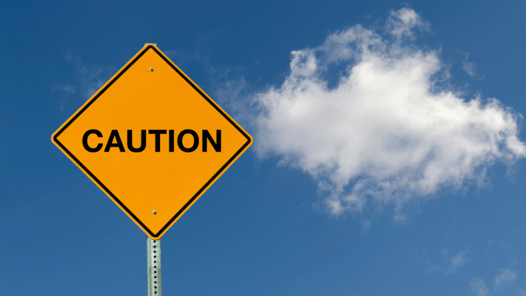 cautionと書かれた標識と青空